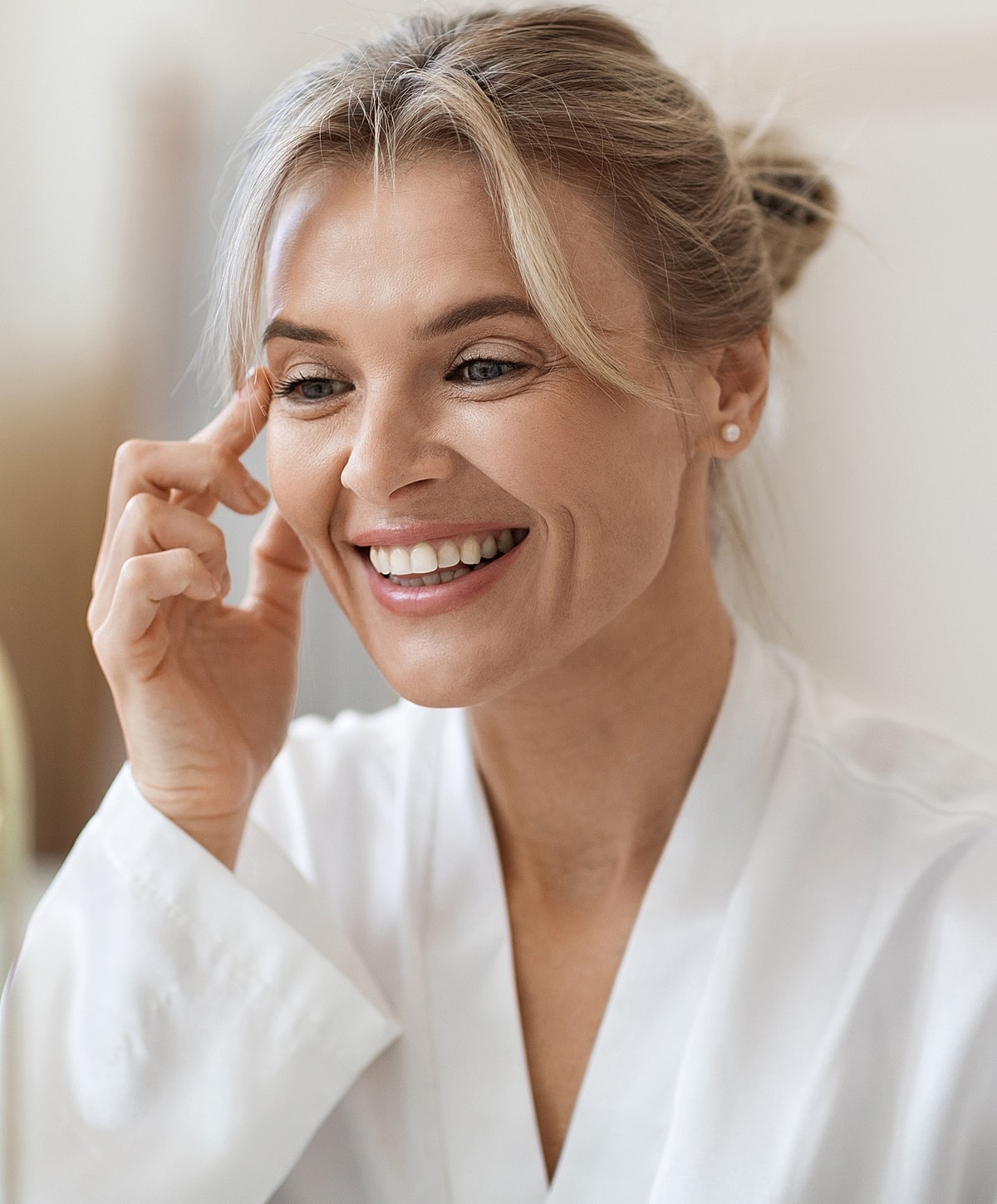 Smiling woman in white robe, joyful expression.