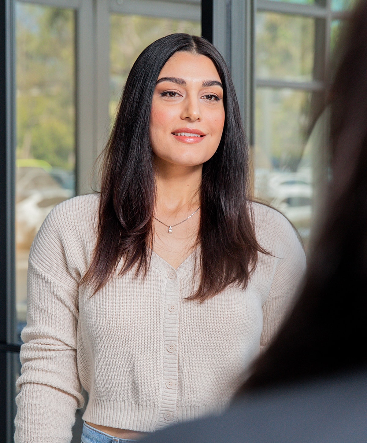 Woman smiling in a bright indoor setting.