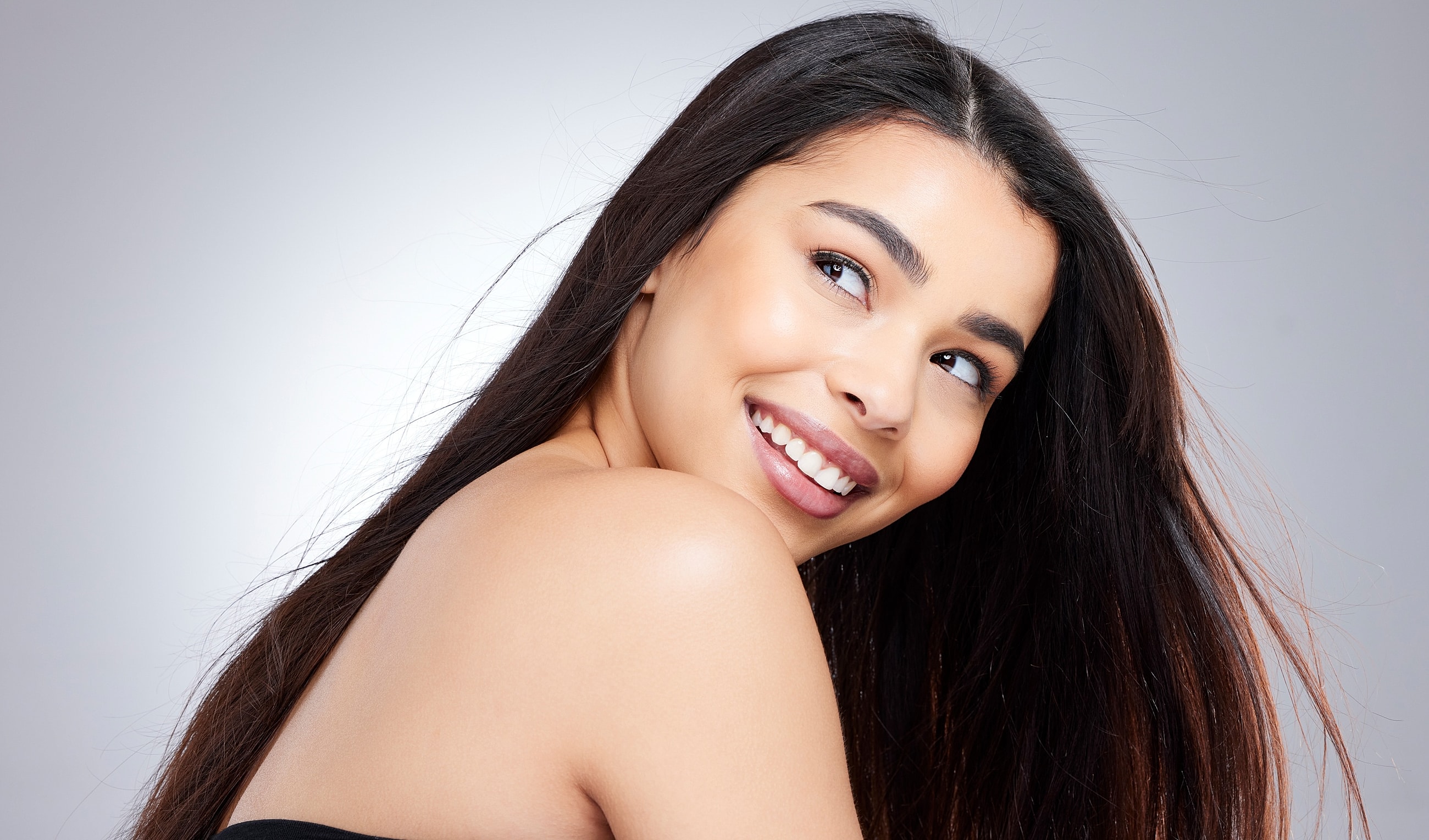 Smiling woman with long dark hair and glowing skin